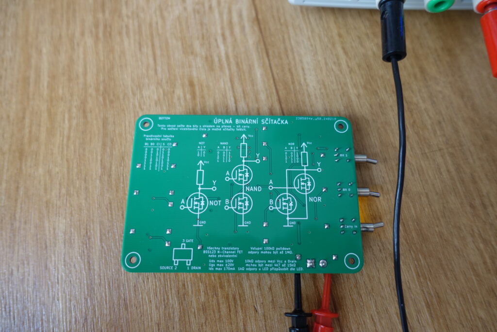 Zadní strana plošného spoje s natištěnými schématy NOT, NAND a NOR hradel z MOSFET tranzistorů.