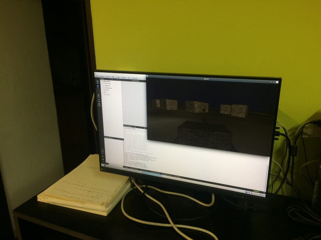 Tank s hlavní, před ním několik krychlí s texturou cihlové zdi.