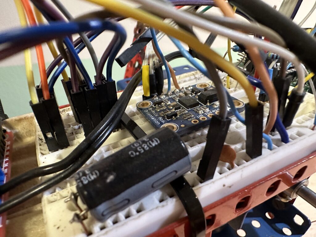 Detail na desku s gyroskopem obklopené chumlem drátů, černým kondenzátorem a červeným rámem z Merkuru.