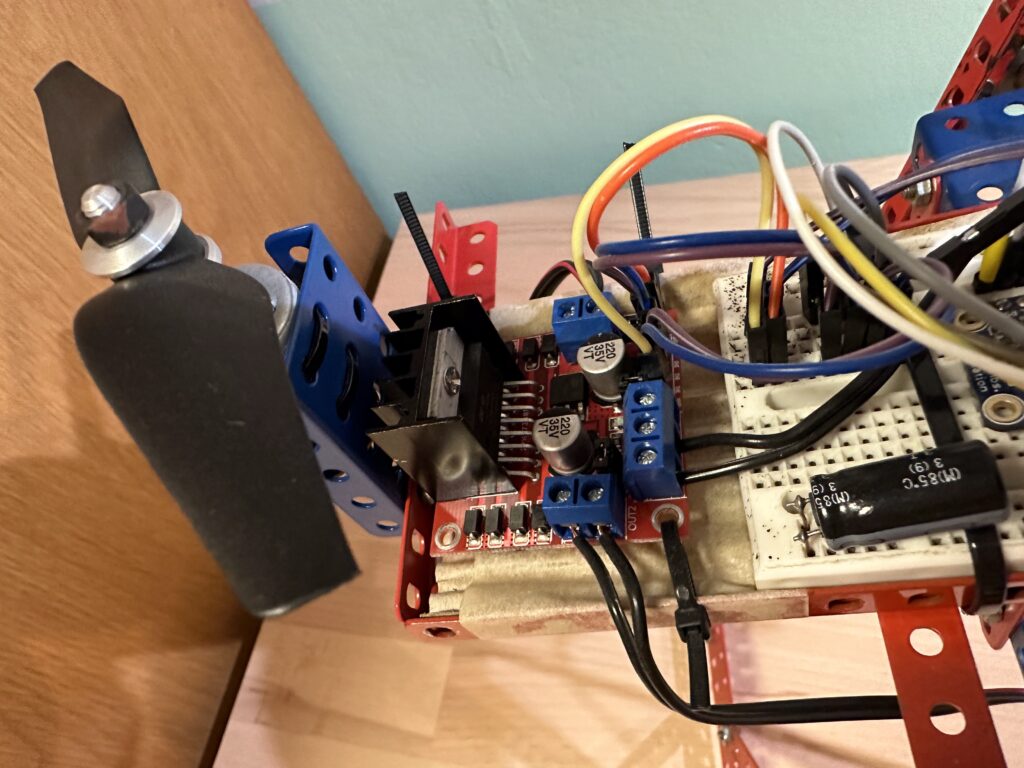 Blízký pohled na elektroniku s motorem, vícebarevnými dráty, kondenzátory a montáží na merkurový rám.