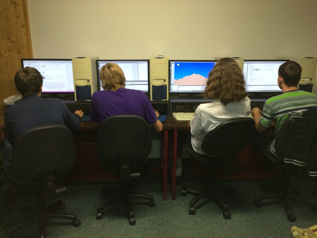 Studenti u počítačů programují hru typu Scorched Earth