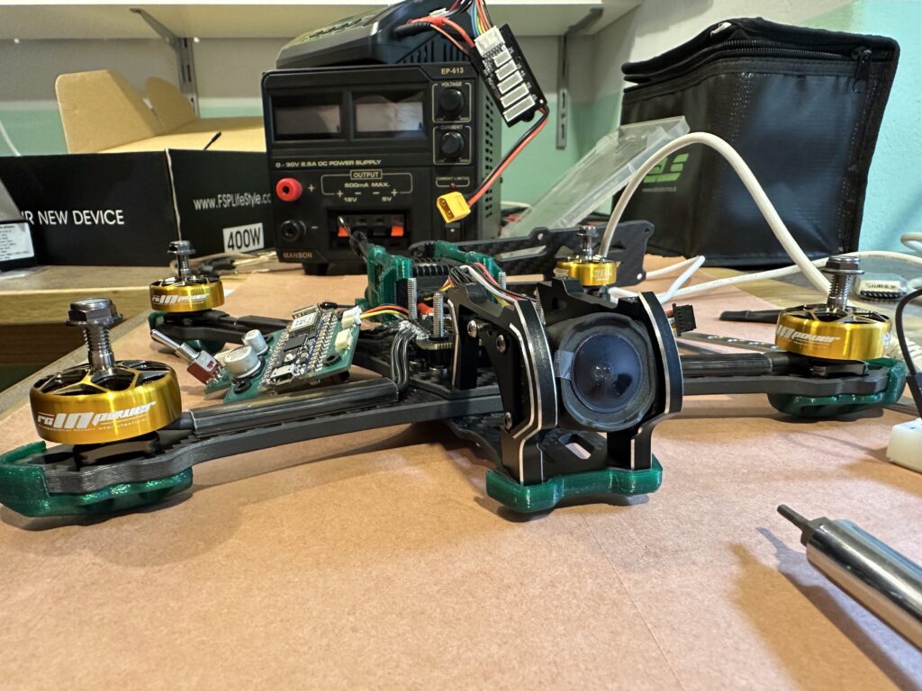Téměř dokončený FPV dron s vlastním letovým počítačem leží na stole.