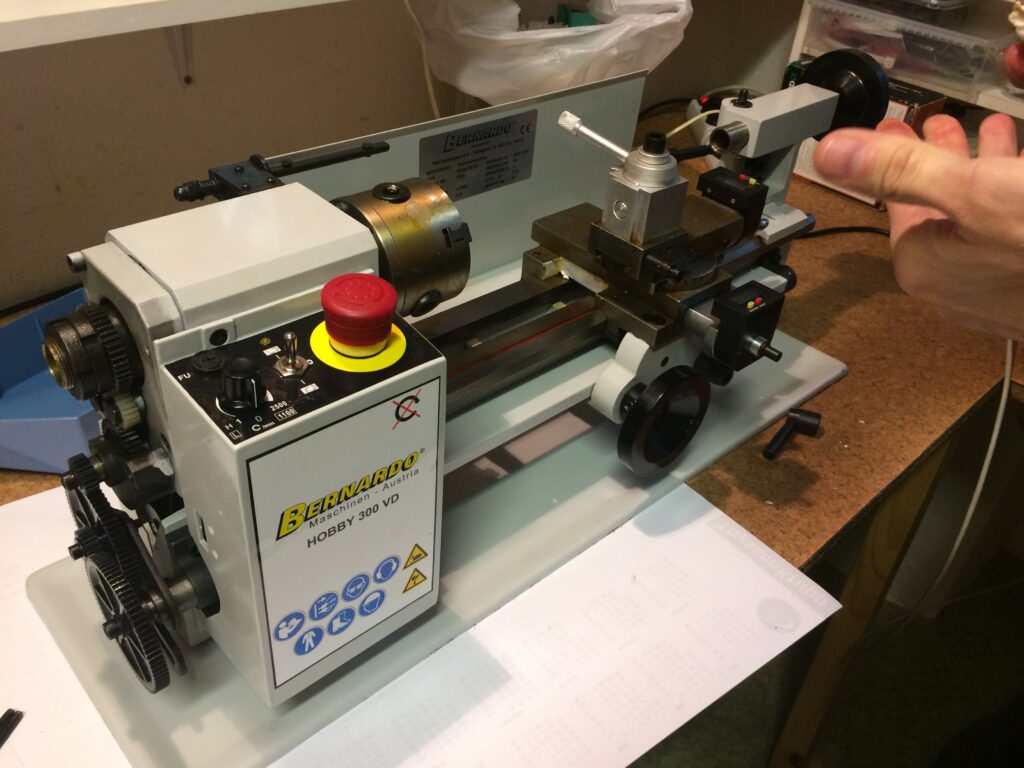 Minisoustruh Bernardo Hobby 300 VD s ovládacím panelem, červeným stop tlačítkem a rukou, která něco drží.