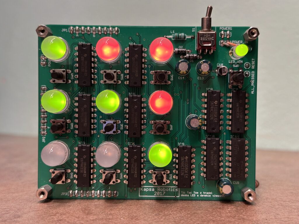 Zelená deska s tištěnými spoji se zelenými a červenými LED diodami, elektronickými součástmi a nápisem "Kapsa Robotics 2017."